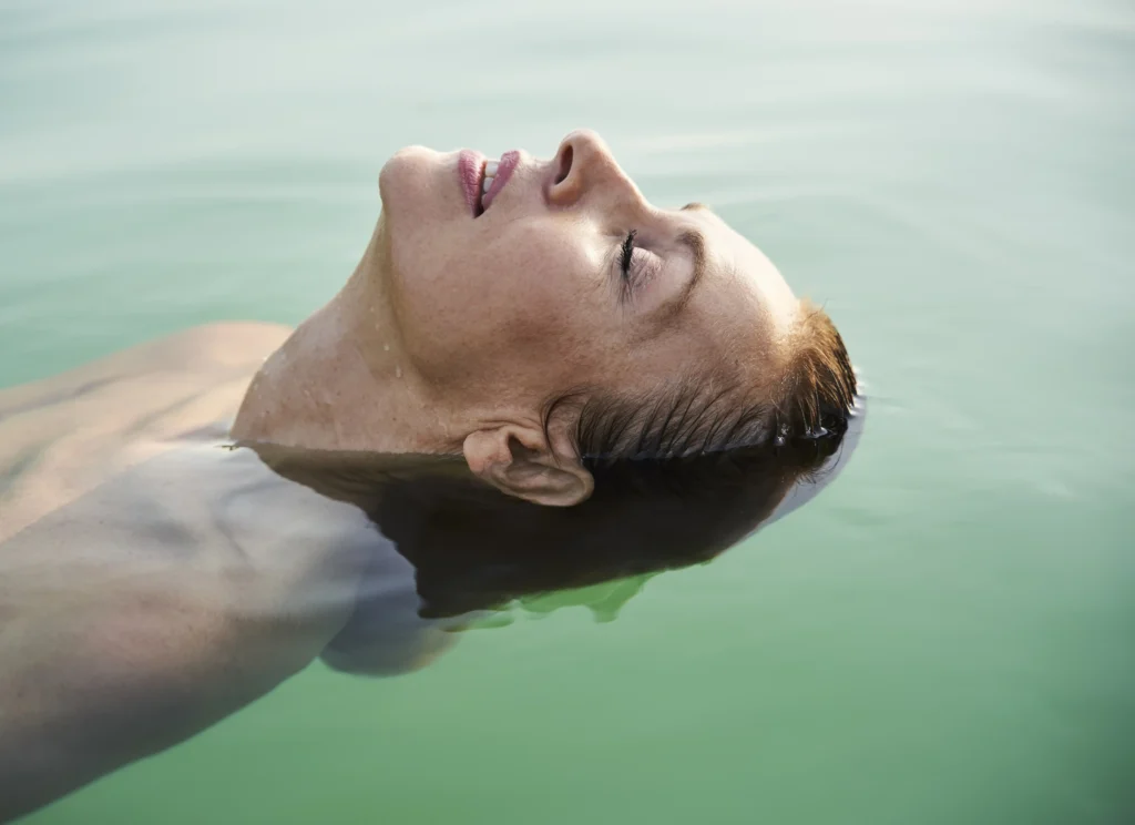 mature woman floating in a lake with closed eyes