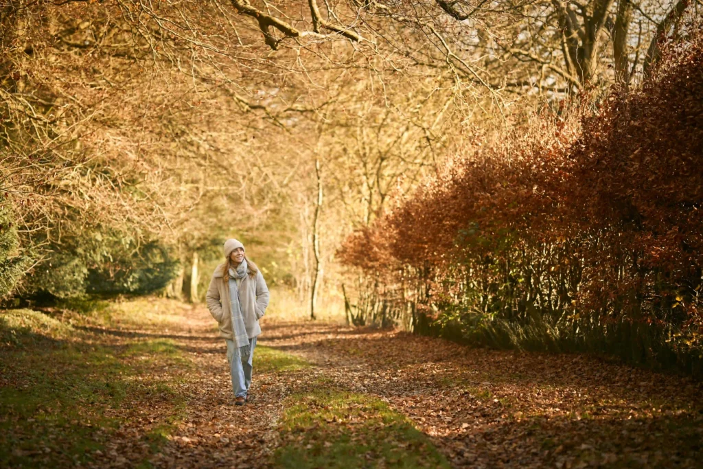 smiling woman on walk through autumn park or count